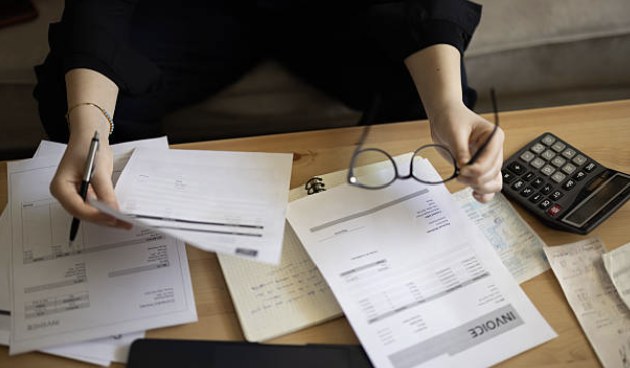 Invoices, receipts and a calculator laid out across a desk