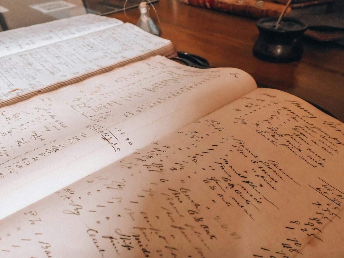 Open ledger books filled with handwritten entries on a wooden desk